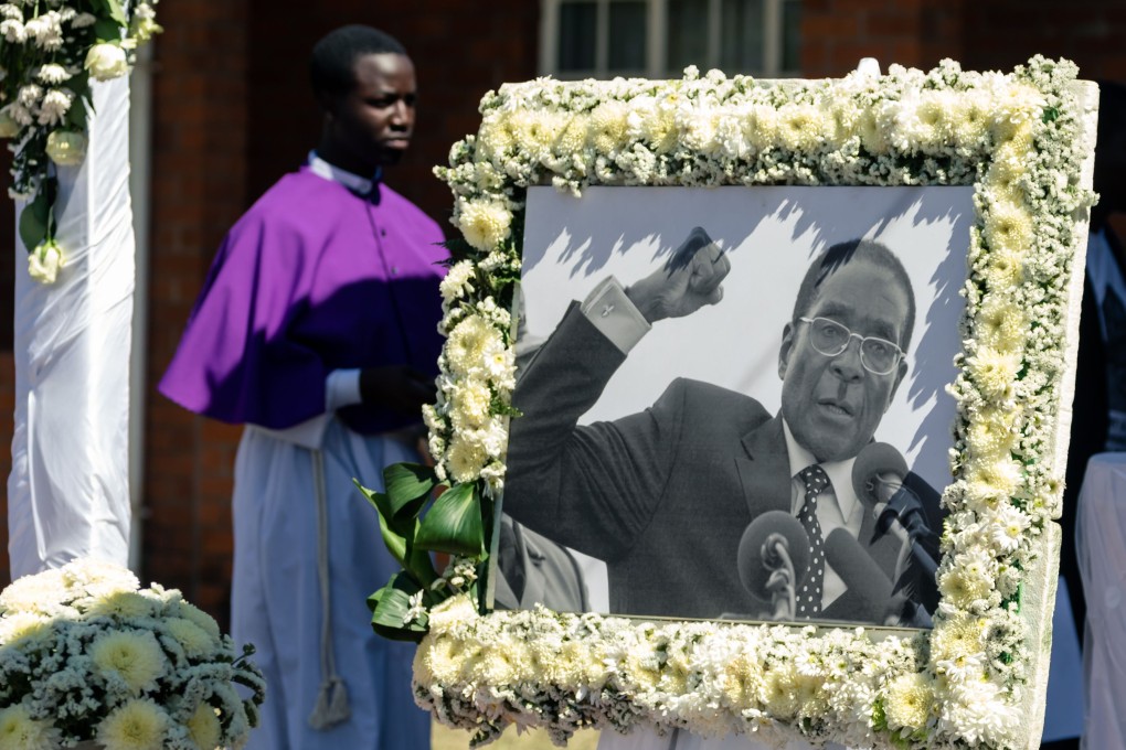 A priest walks past a portrait of Robert Mugabe during the burial of the former Zimbabwe leader. Photo: AFP