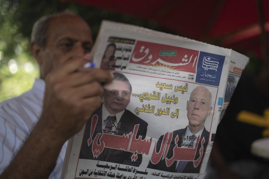 A man reads a newspaper showing candidates Kais Saied, right, and Nabil Karoui on its front page in Tunisia. Photo: AP