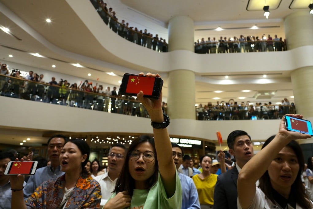 Chanting, singing and holding up images of the Chinese flag, a pro-Beijing flash mob appears at Pacific Place in Admiralty, Hong Kong. Photo: AFP