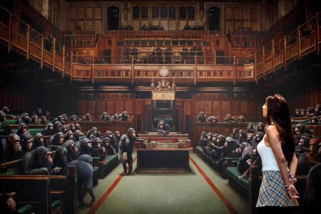A gallery assistant poses with Banksy’s Devolved Parliament in London on Friday. Photo: AFP