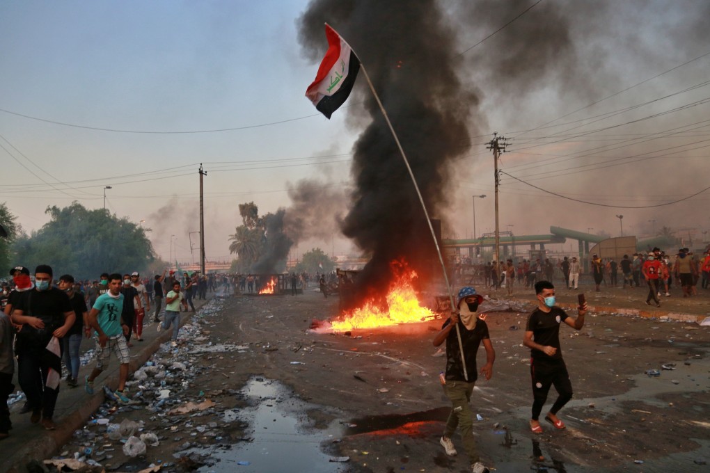 Anti-government protesters set fires and close a street during a demonstration in Baghdad. Photo: AP