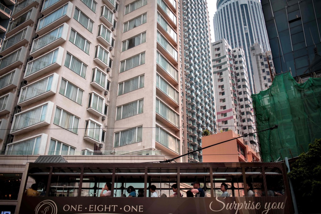People ride a tram moving past residential buildings in Wan Chai. Hong Kong property prices are among the highest in the world. Photo: AFP