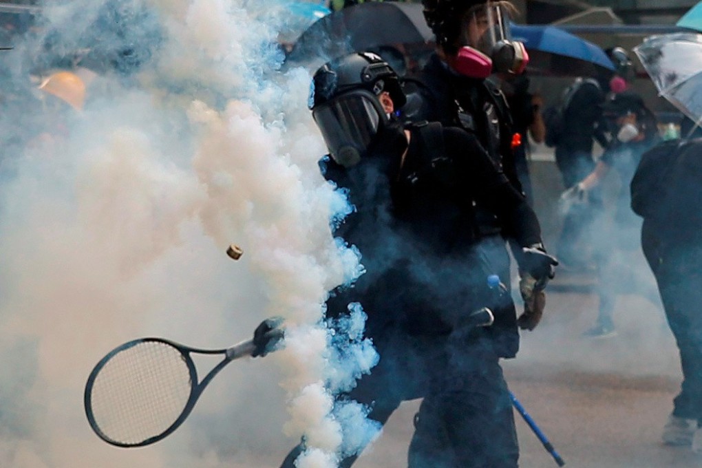 An anti-government protester uses a tennis racket to hit a tear gas canister during a clash with riot police in Hong Kong. Photo: Reuters