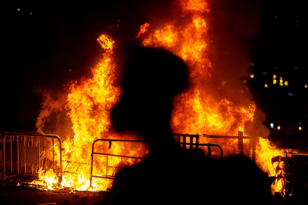 An anti-government protester stands near a fire in Wong Tai Sin after leader Carrie Lam announced emergency laws banning face masks at protests. Photo: Reuters