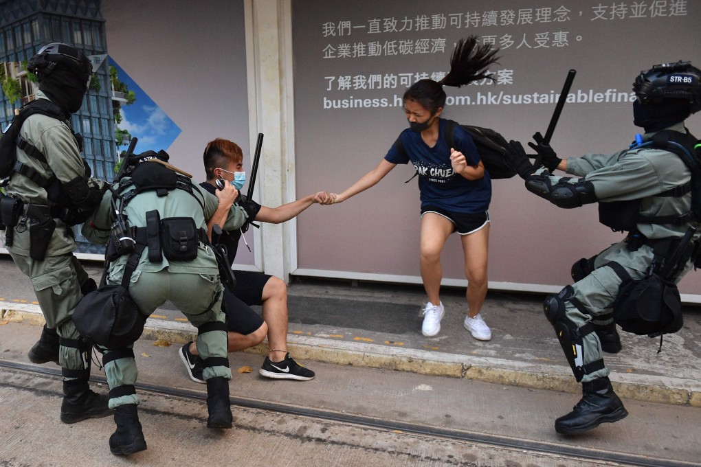 Hong Kong police chase down a woman wearing a face mask in the city’s central district on Saturday. Photo: AFP