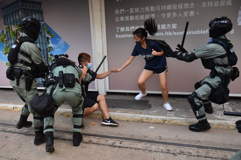 Hong Kong police chase down a couple wearing face masks in Central on October 5. Photo: AFP