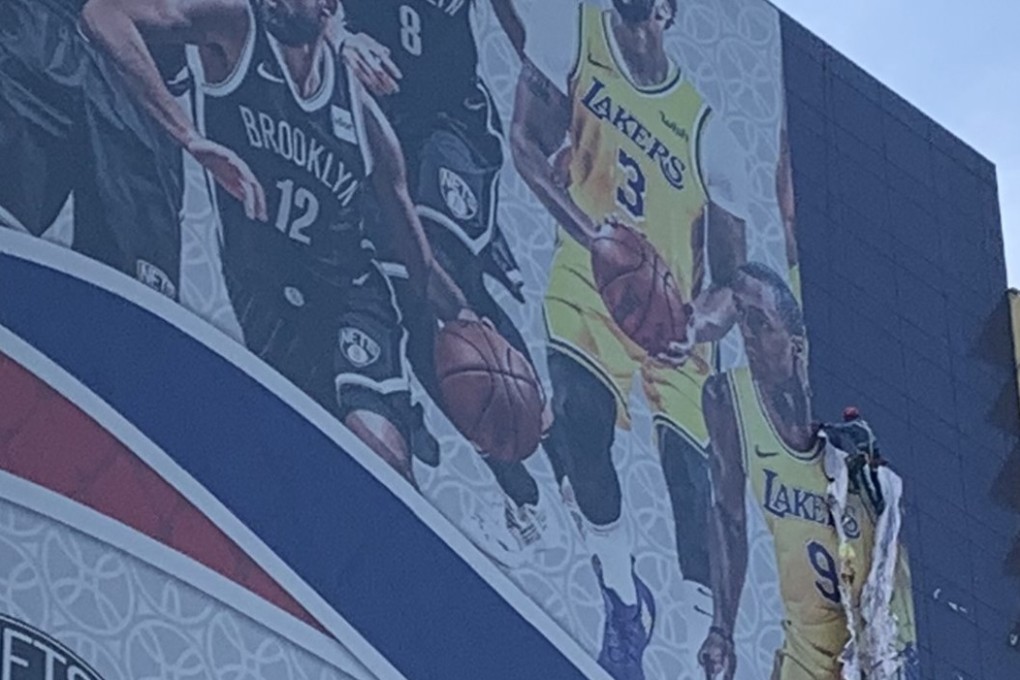 A worker tears down a poster promoting NBA preseason games scheduled to be held in Shanghai. Photo: Thomas Yau