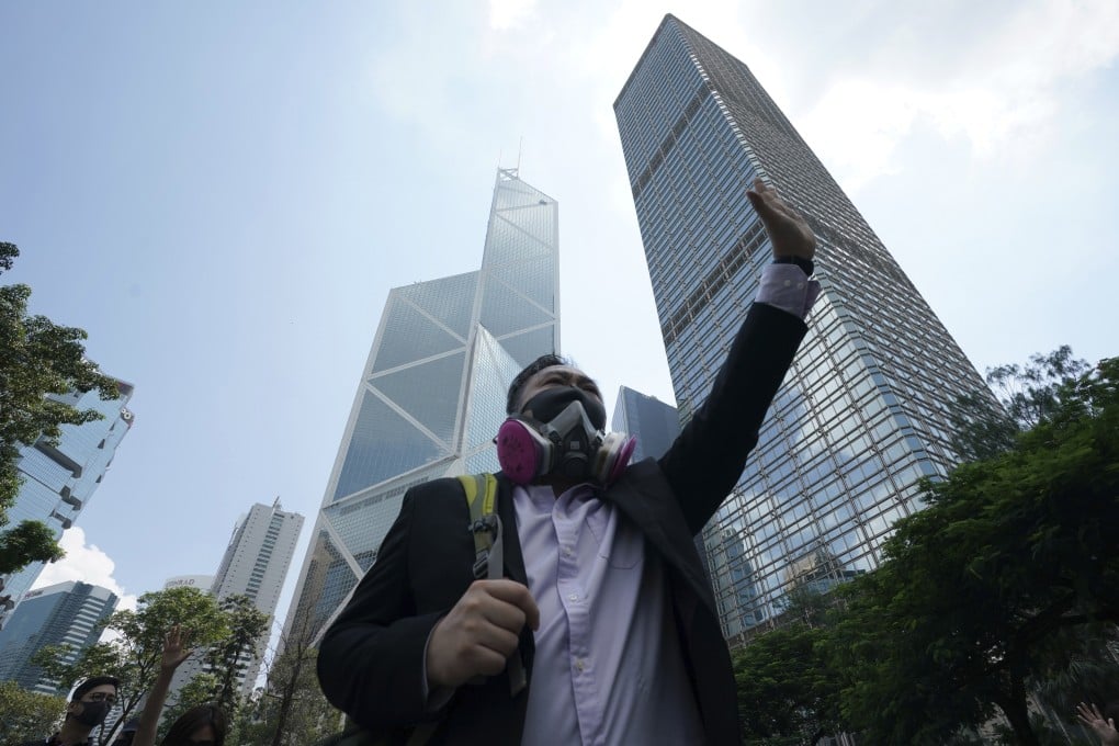 A protester wears a gas mask and holds up his hand to represent the five demands protesters are making of the government, at a rally on October 4, ahead of the ban on wearing masks. Photo: AP