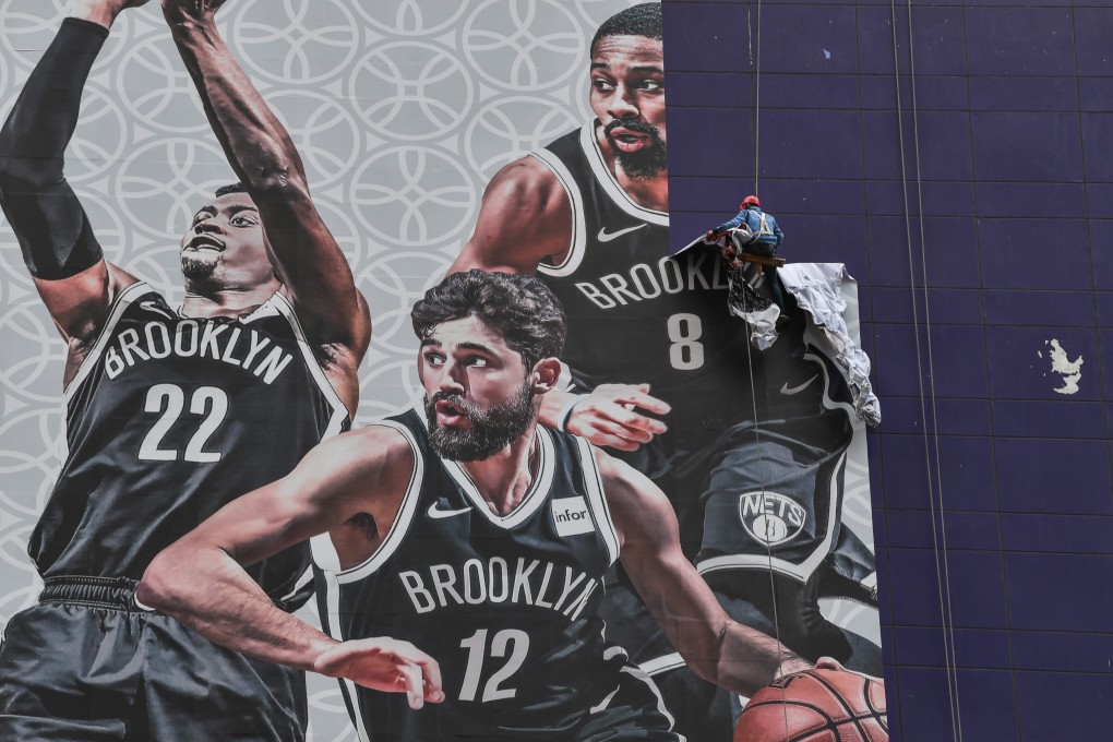 A worker strips off a giant poster promoting the NBA preseason game in Shanghai. Photo: Bloomberg