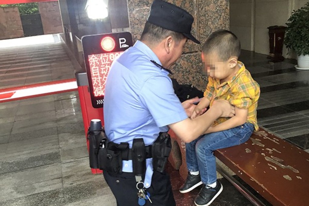 An officer from Dazhu district police station in Chongqing speaks to the little boy found asleep in a car park. Photo: Weibo