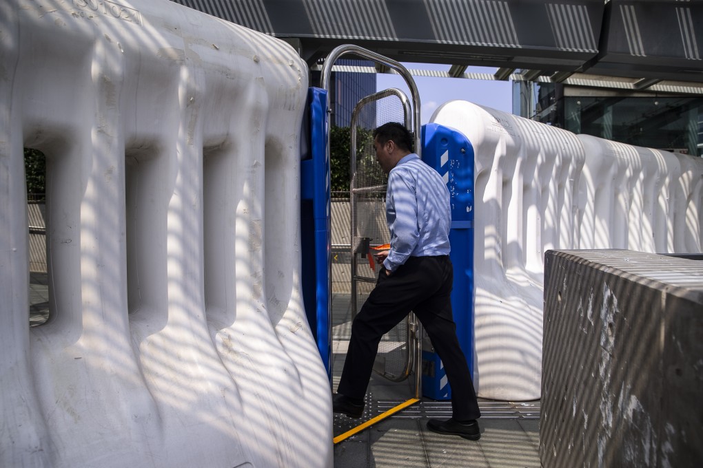 A pedestrian steps through a barrier at the Legislative Council in Admiralty. If the government continues to perform dismally, pro-government parties might lose seats in the Legco election next September. Photo: Bloomberg