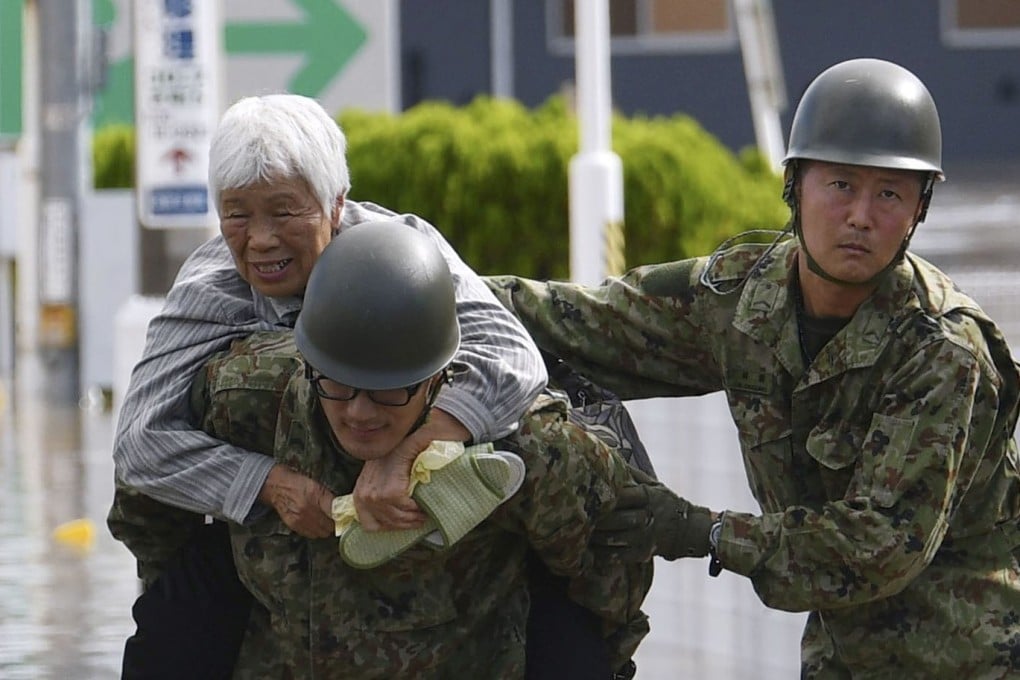 A local resident is rescued by Japanese Self-Defence Forces soldiers in Motomiya, Fukushima prefecture. Photo: Kyodo