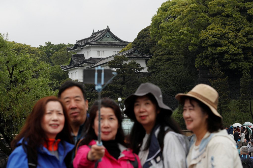Chinese tourists take photos in front of the Imperial Palace in Tokyo, Japan. Photo: Reuters