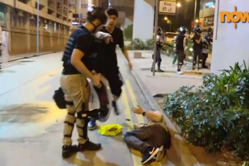 An officer stands over a man, identified as a driver for Now News, before he was bound and moved into the police station. Photo: Handout