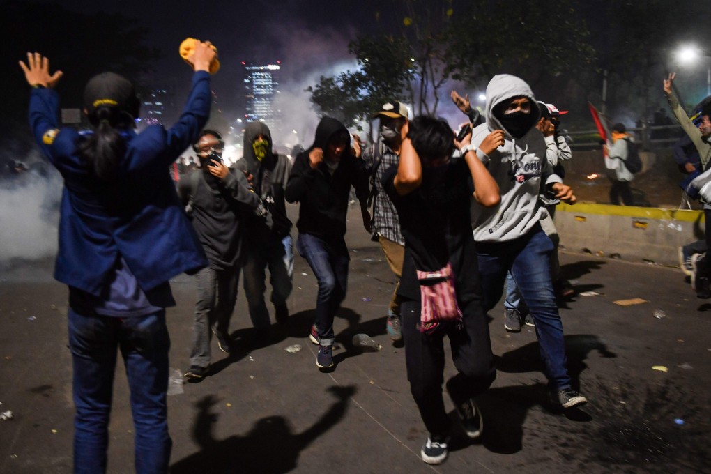 Indonesian students run from police shooting tear gas during a protest outside the parliament building in Jakarta in September 2019. Photo: AFP