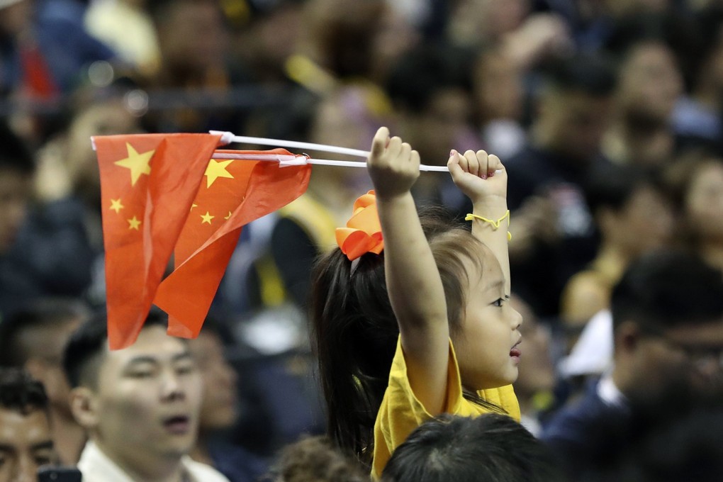 A child holds up two Chinese national flags as she watches a pre-season NBA basketball game between the Brooklyn Nets and Los Angeles Lakers at the Mercedes Benz Arena in Shanghai on October 10. Photo: AP
