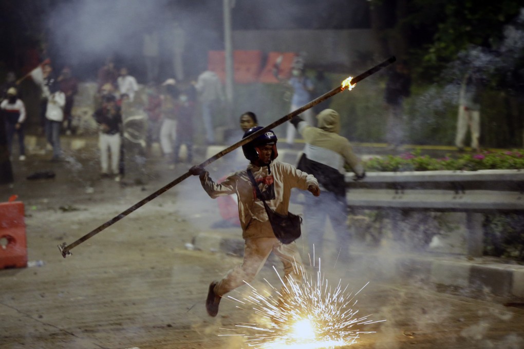 A student protester throws a burning stick at riot police during a clash in Jakarta on September 30. Photo: AP