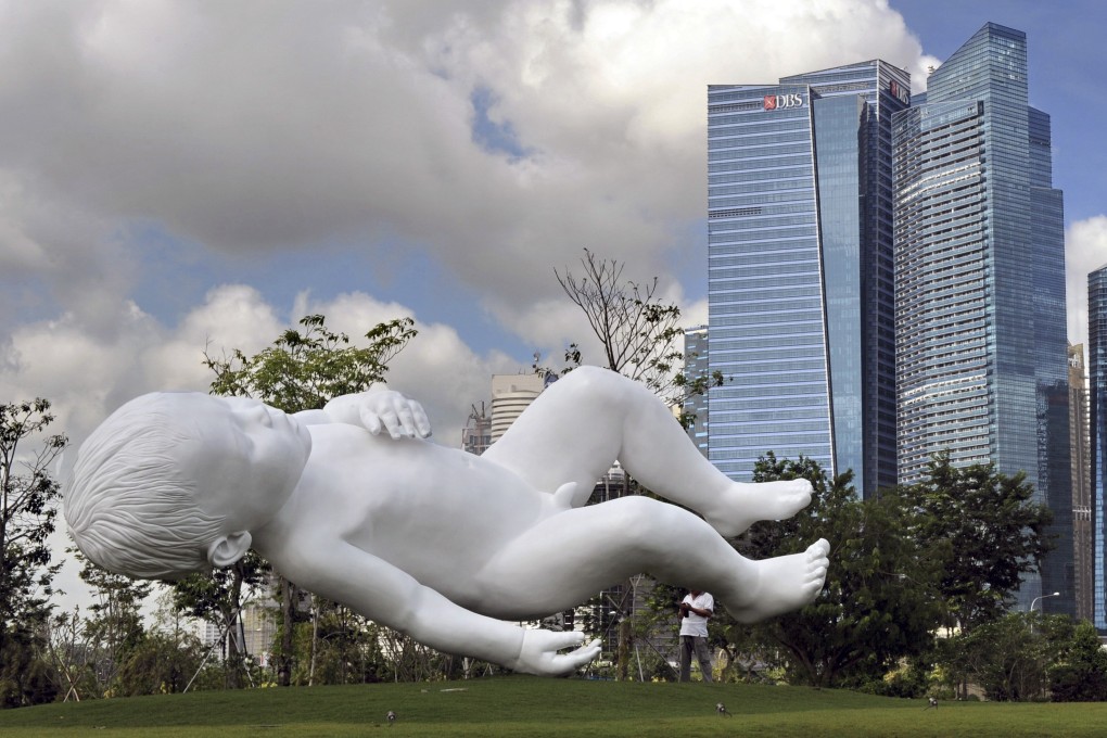 A white painted bronze sculpture of a baby titled “Planet” by British artist Marc Quinn appears to float at Gardens by the Bay in Singapore in January 2013. Photo: AFP