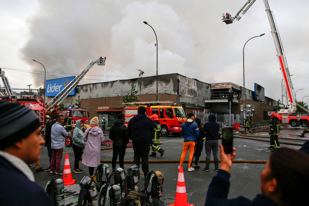 Firefighters extinguish a fire in a supermarket in Santiago, in which three people died. Photo: AFP