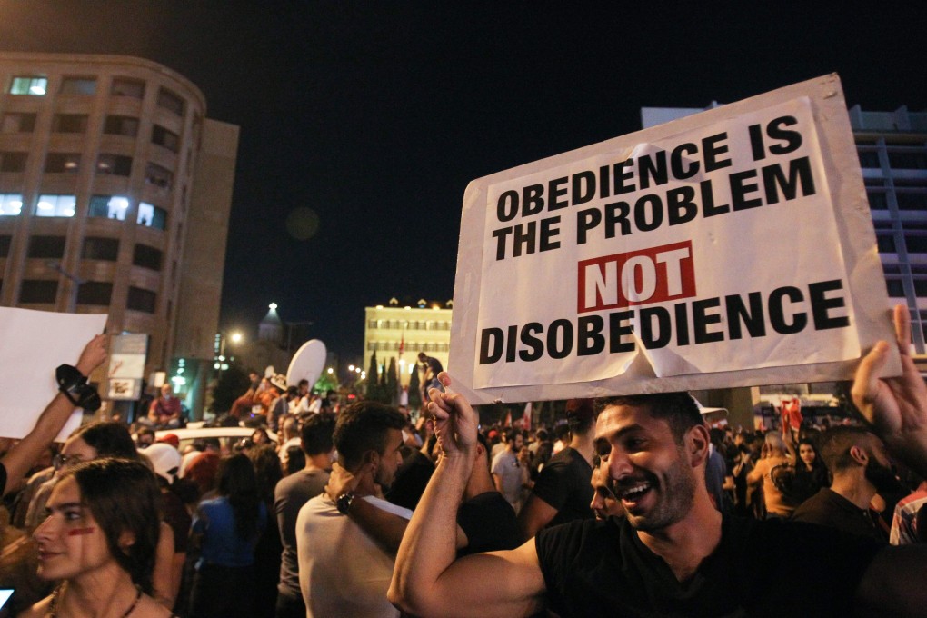A Lebanese protester lifts a placard during a rally in downtown Beirut on the third day of demonstrations against tax increases and official corruption. Photo: AFP