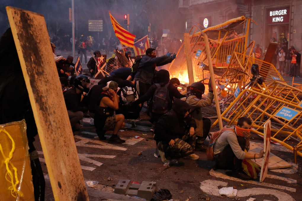 Protesters use fences as a barricade during clashes near the Police headquarters in Barcelona. Photo: AFP