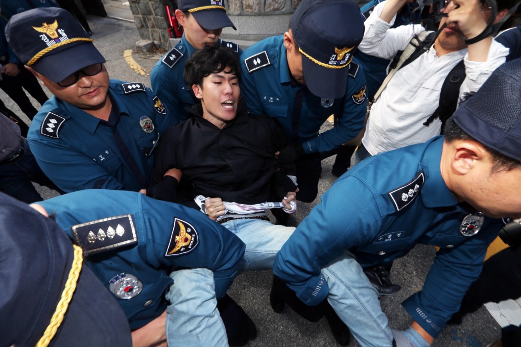 South Korean police officers detain a protester at Habib House in Seoul on Friday. Photo: EPA-EFE