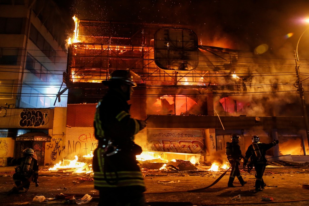 Firemen work to put out fire at a supermarket during a protest against the government in Chile. Photo: Reuters