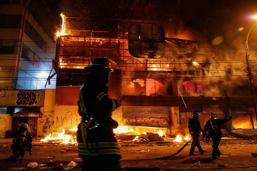 Firemen work to put out fire at a supermarket during a protest against the government in Chile. Photo: Reuters
