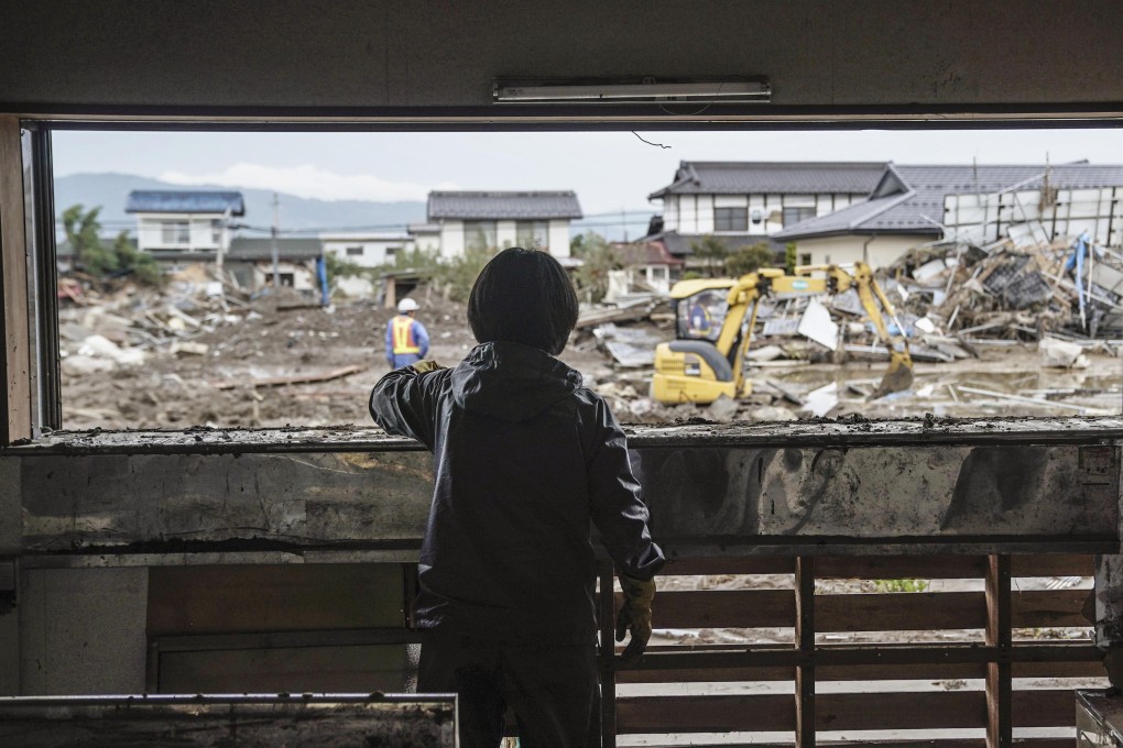 A woman looks out the window of her badly damaged home at the devastation in Nagano caused by Typhoon Hagibis. Photo: Kyodo