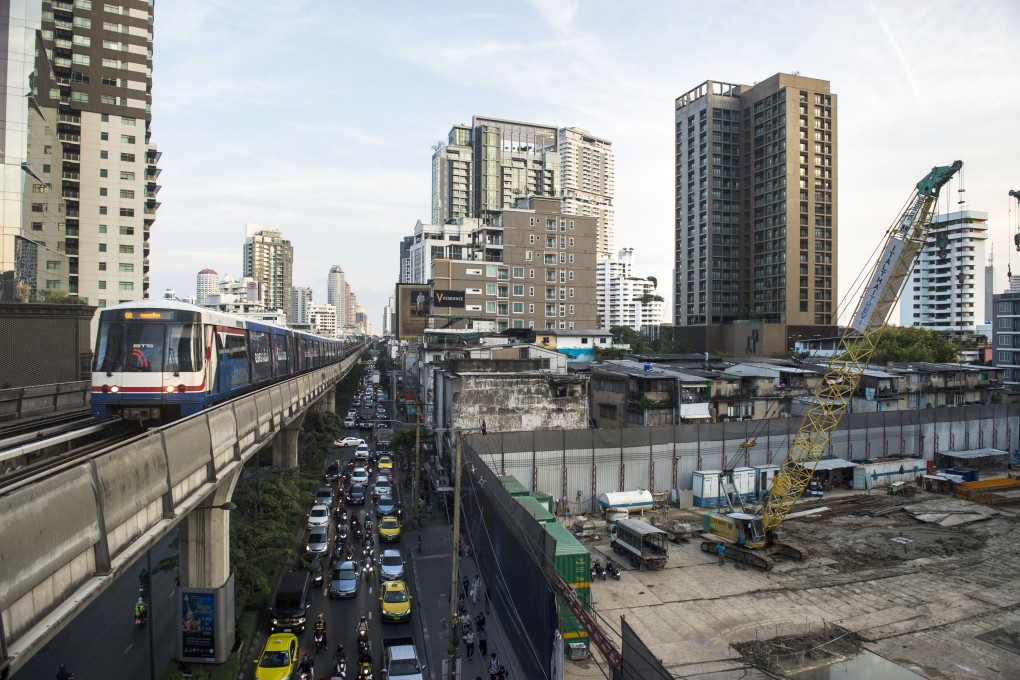 A suburban train passes a building construction site in central Bangkok. Photo: AFP
