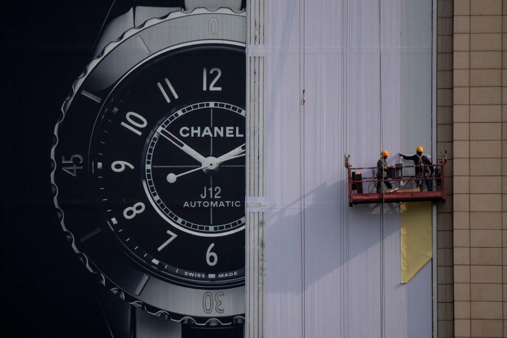 Workers dismantle an advertising hoarding in Beijing. The International Monetary Fund has cited US-China trade tensions as a driving factor for “sluggish global growth”. Photo: AFP