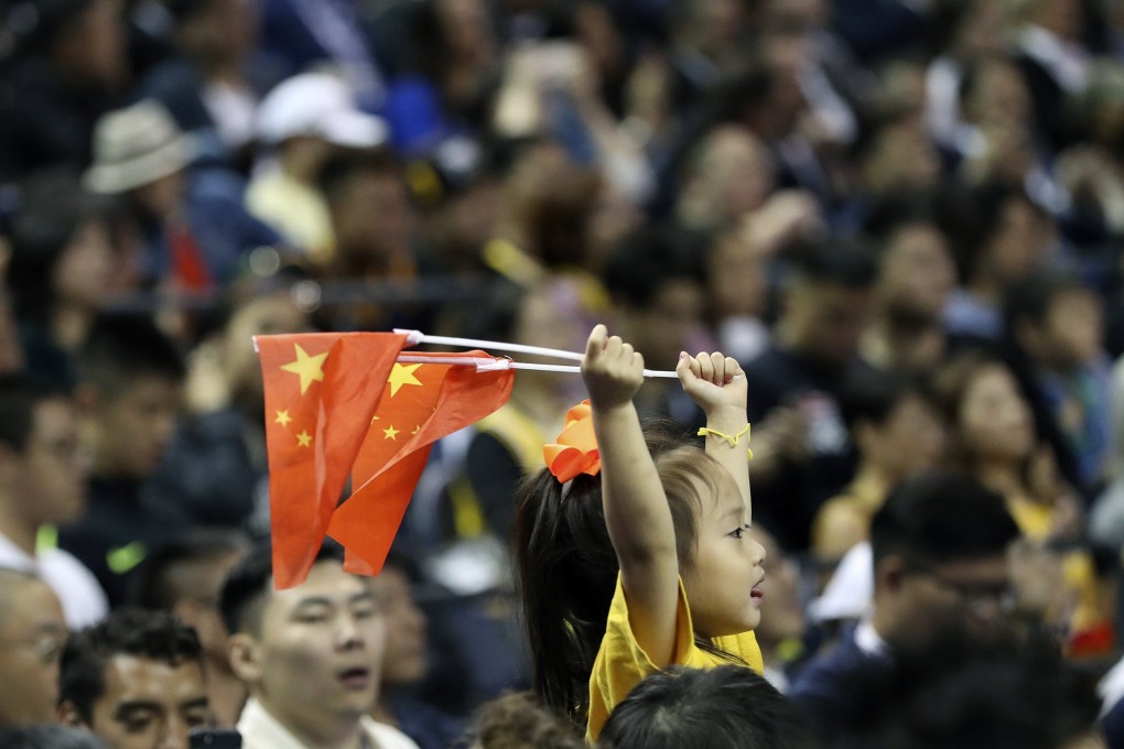 A child holds up two Chinese national flags as she watches a preseason NBA game between the Brooklyn Nets and Los Angeles Lakers in Shanghai, China. Photo: AP