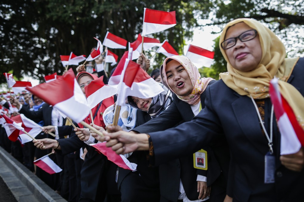 Indonesian presidential palace staff wave national flags as President Joko Widodo leaves for the parliament building. Photo: EPA-EFE
