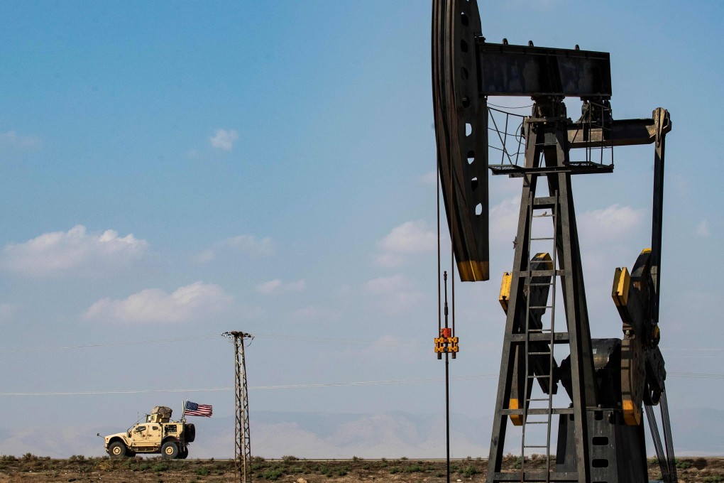 A US military vehicle, part of a convoy arriving from northern Iraq, drives past an oil pump jack in the countryside of Syria's northeastern city of Qamishli. Photo: AFP