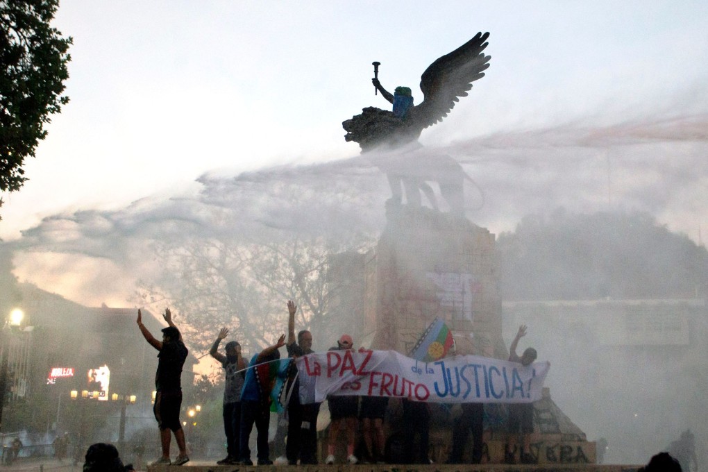 Riot police fire water cannon at demonstrators in Santiago. Photo: AFP