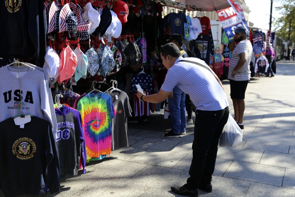 A Chinese visitor takes pictures of Washington t-shirts at a tourism kiosk in the US capital. Photo: AP
