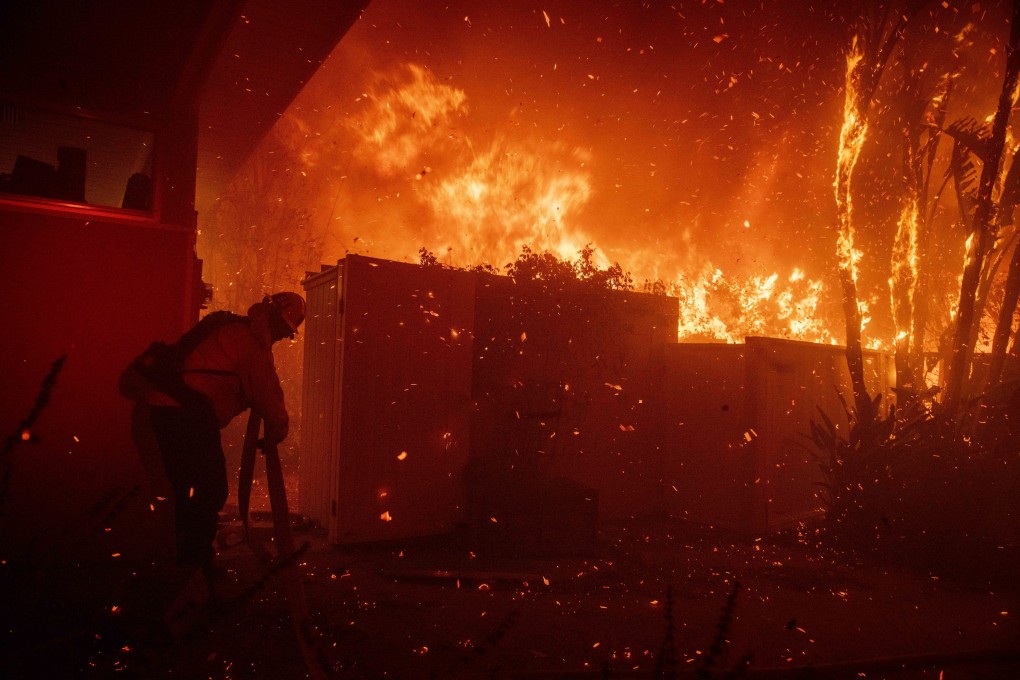 Firefighters try to save a home on Tigertail Road from the Getty fire in Los Angeles. Photo: AP