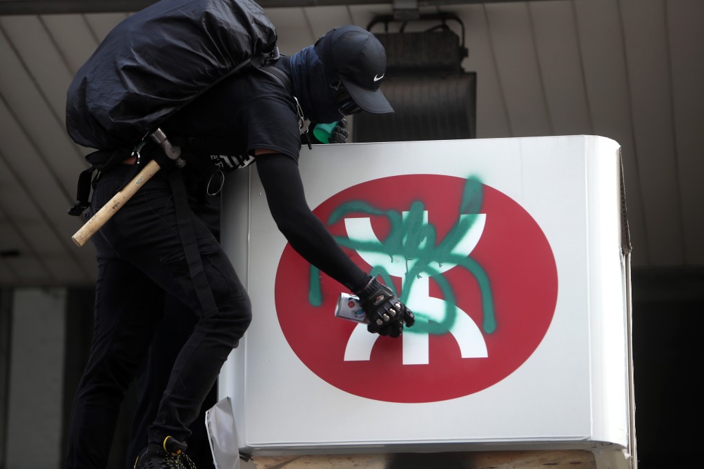 A protester vandalises an MTR sign at Yau Ma Tei station. Photo: Winson Wong
