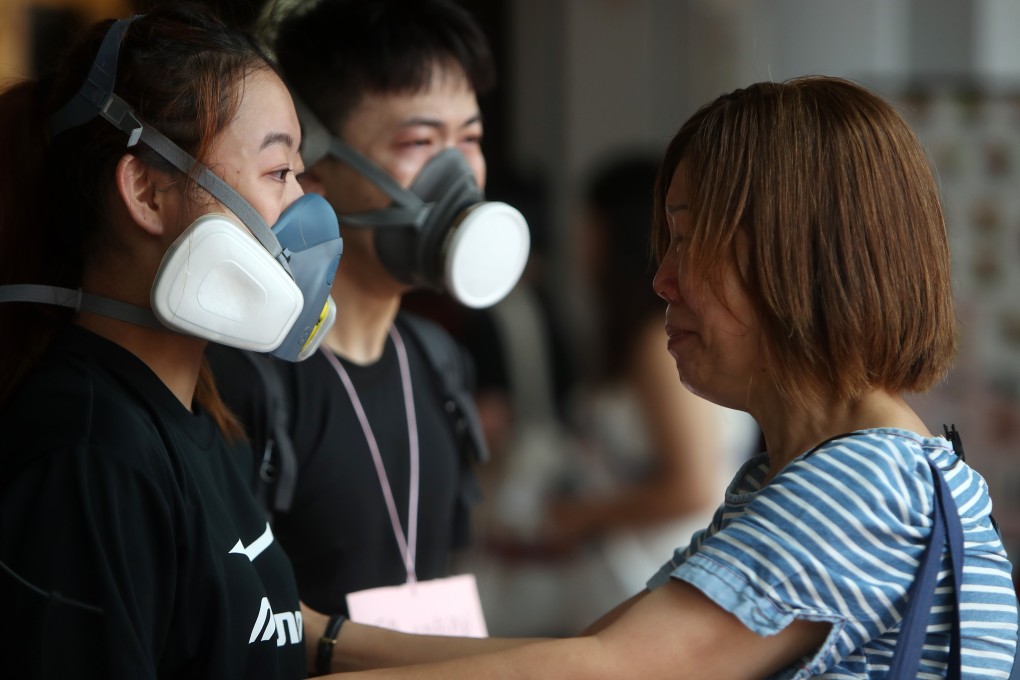 A woman cries for anti-government protesters as they hand out face masks to local residents, outside Kwai Fong MTR station on August 12. Riot police had fired tear gas in the area the night before. Photo: Winson Wong