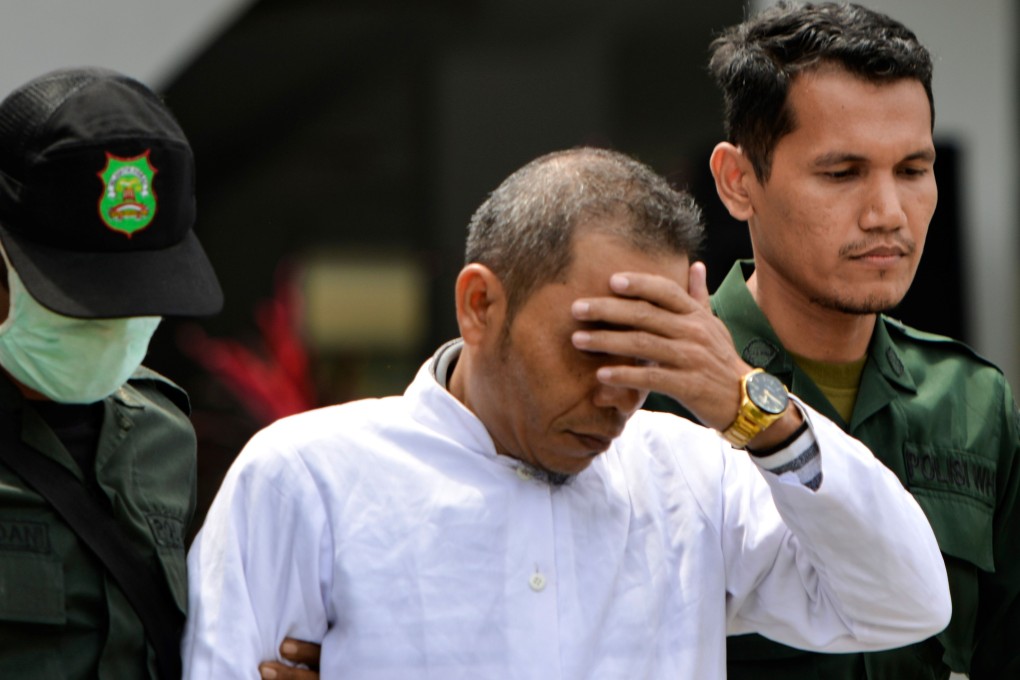 Aceh Ulema Council member Mukhlis, centre, is escorted by members of the sharia police before being publicly whipped in Banda Aceh on Thursday. Photo: AFP