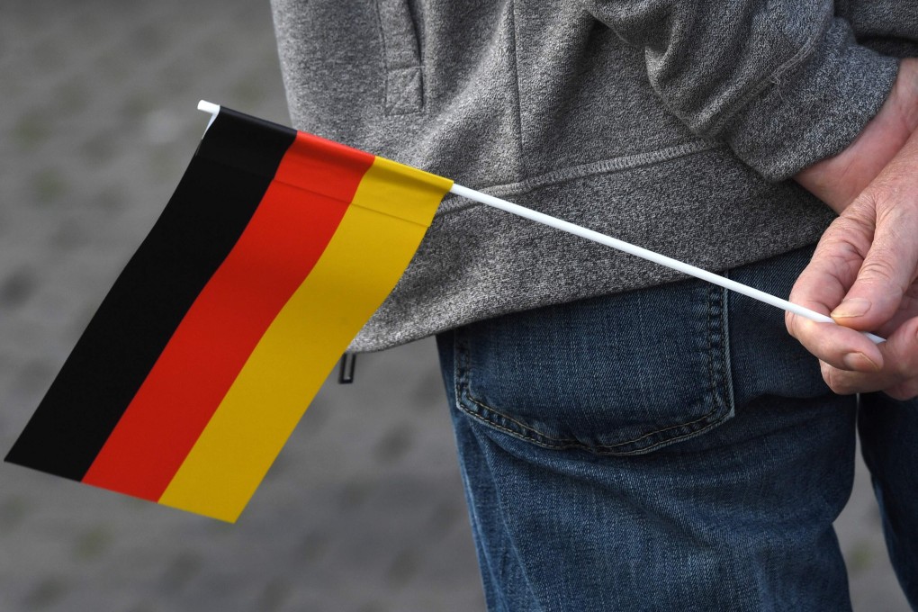 A man holds a German national flag during an election campaign event for Germany’s far-right AfD. Photo: AFP