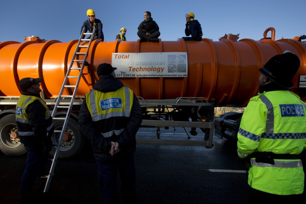 Police prepare to remove a protester from the top of a vehicle waiting to enter an exploratory drill site for fracking in Manchester, England. Photo: AP