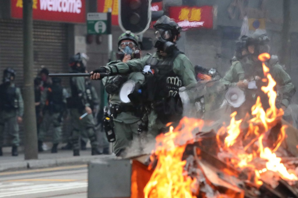 Police march down a road in Wan Chai to disperse protesters as a barricade burns. Photo: Felix Wong