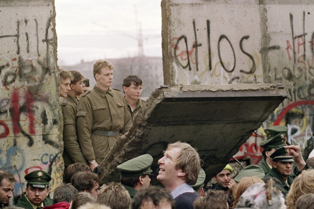 On November 11, 1989 West Berliners crowd in front of the Berlin Wall as they watch East German border guards demolish a section of the wall in order to open a new crossing point between East and West Berlin, near the Potsdamer Square. File photo: AFP