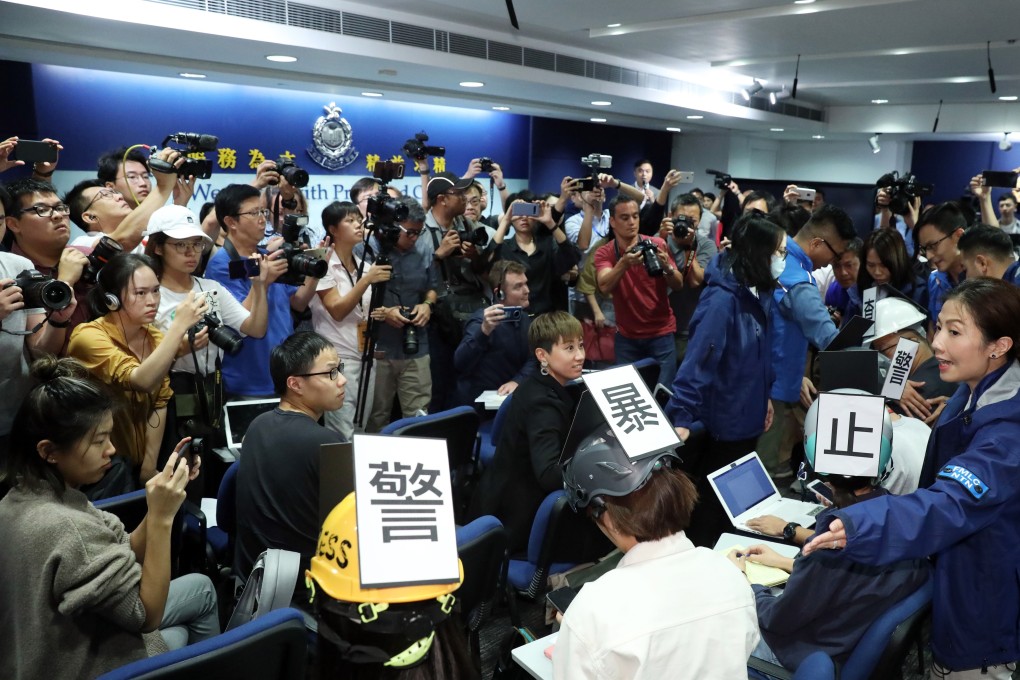 Journalists wearing helmets with banners attend a police press conference in Wan Chai. Photo: Nora Tam