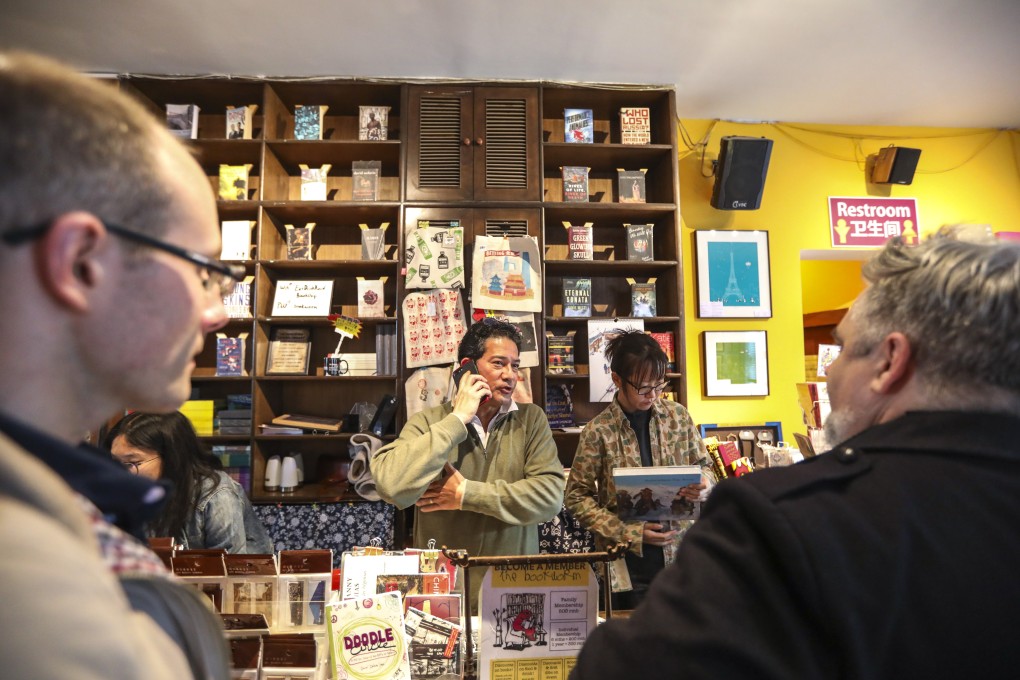 David Cantalupo, co-founder of The Bookworm, takes a phone call at the bookstore in Beijing on Tuesday as customers look on. The store, a cornerstone of the expatriate literary community in the Chinese capital, announced it would close on November 11 having been unable to renew its lease. Photo: Simon Song