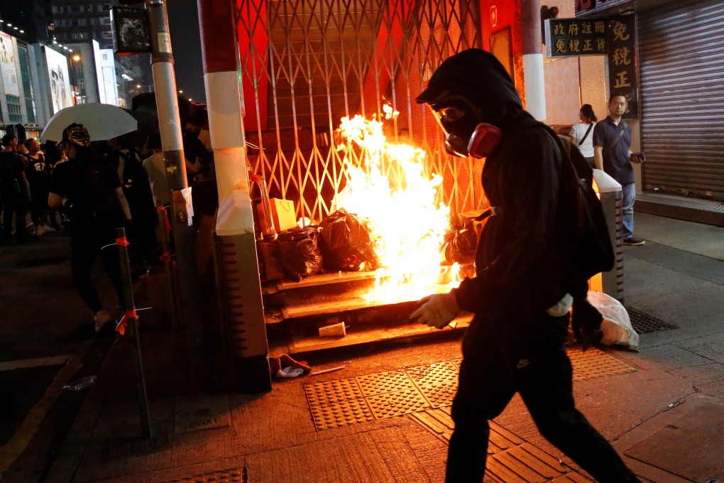 A protester walks past a burning barrier outside Mong Kok MTR station on October 27. Photo: Reuters