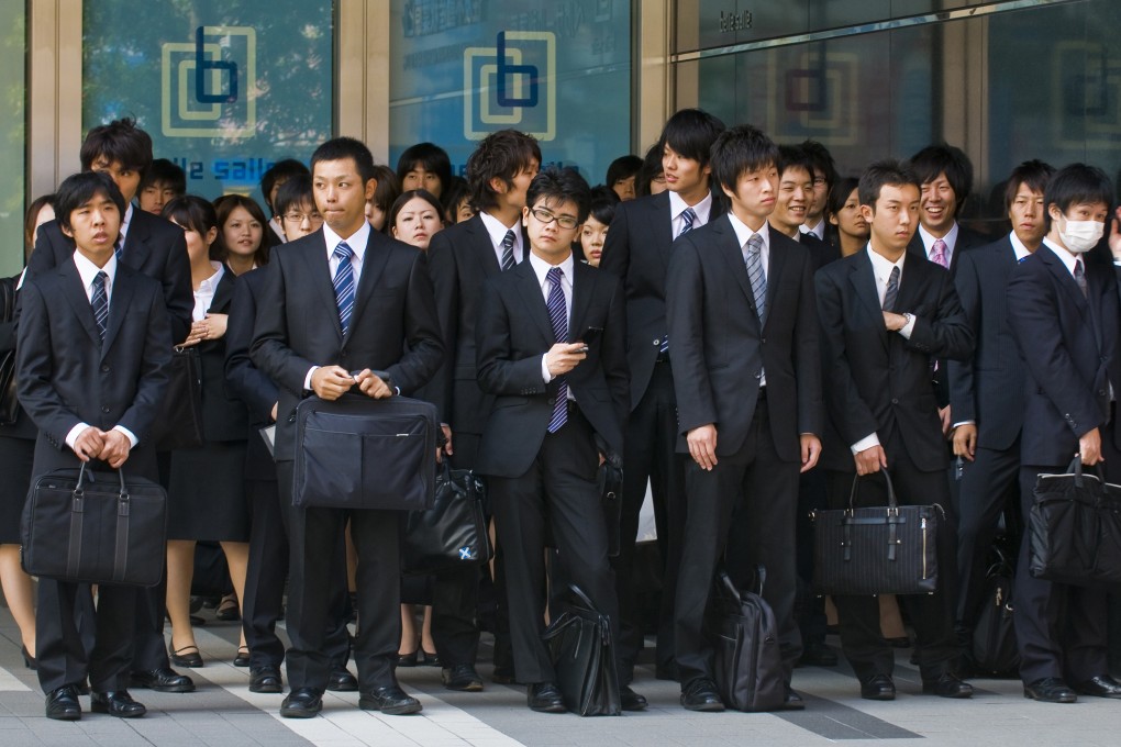 Japanese office workers stands outside an office building in Tokyo Japan. Microsoft in Japan trialled a four day work week. Photo: Shutterstock