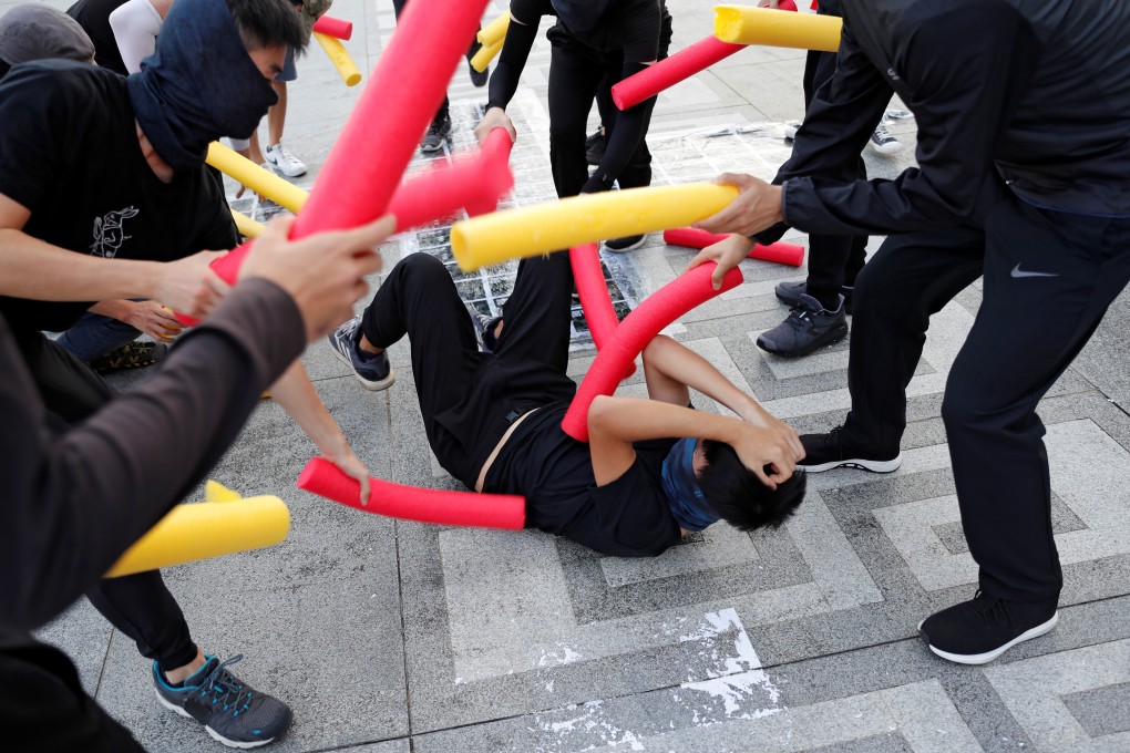 A masked participant is hit with foam sticks during a self-defence class organised by a student union at the Chinese University of Hong Kong. Photo: Reuters