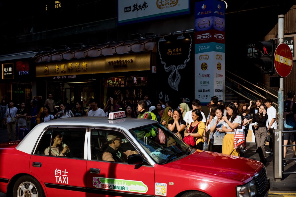 A Hong Kong taxi drives past pedestrians in the busy commercial and shopping area of Causeway Bay. Photo: Bloomberg